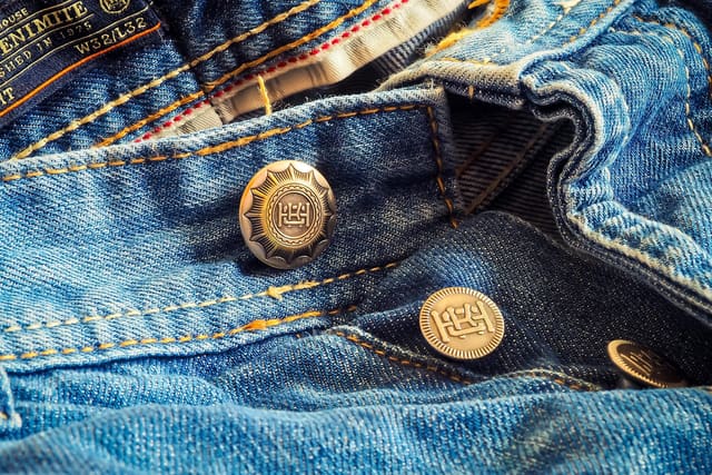 Antique-metal shank button and rivets on a denim waistband