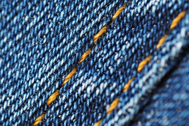 Close-up of orange contrast topstitching along a denim seam