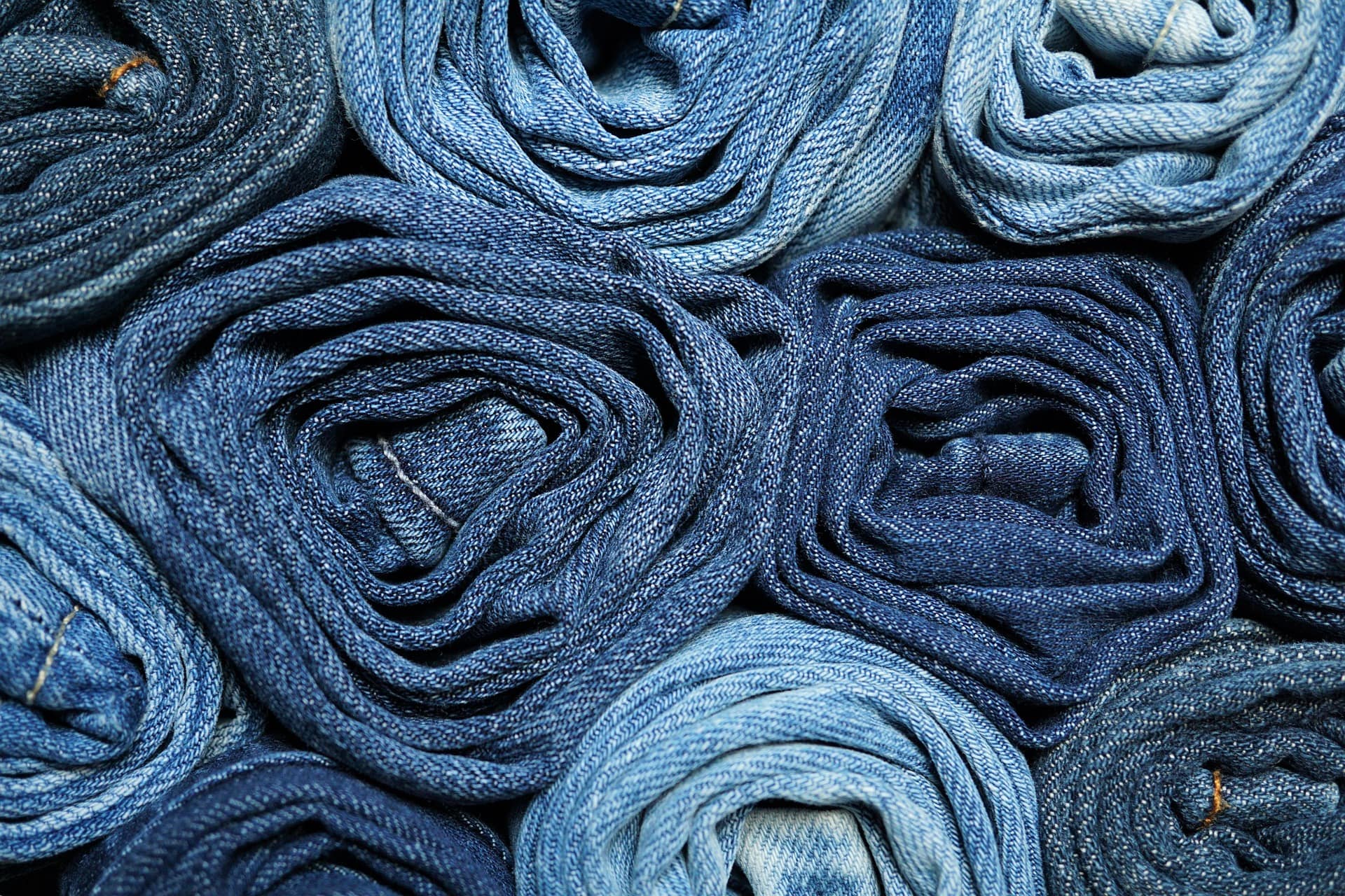 Rolled bolts of selvedge denim stacked in the cutting room